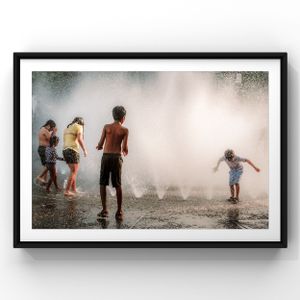 Silhouetted figures play in misty water sprays during a hot summer day.