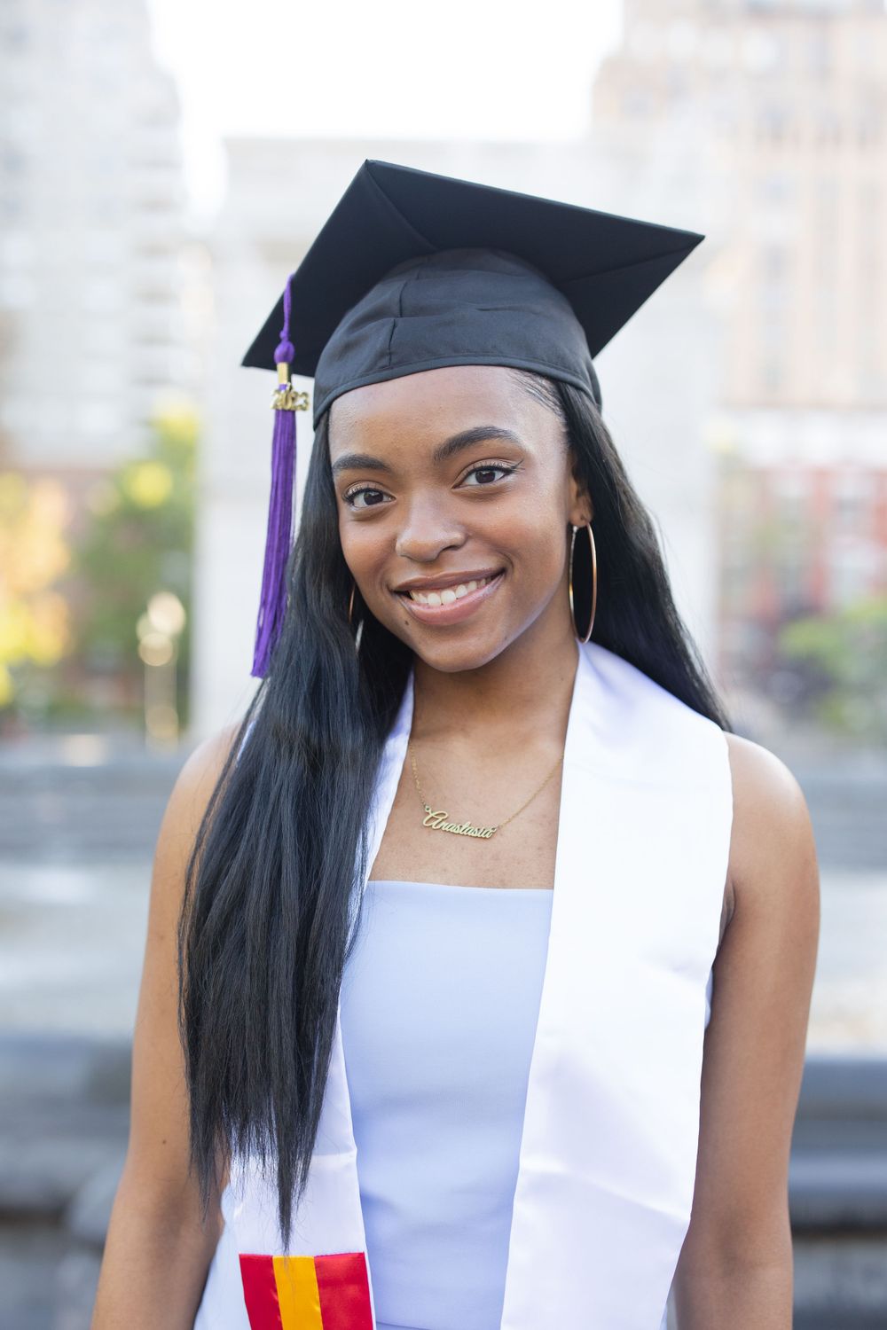 Graduate wearing cap with purple tassel and white graduation stole.