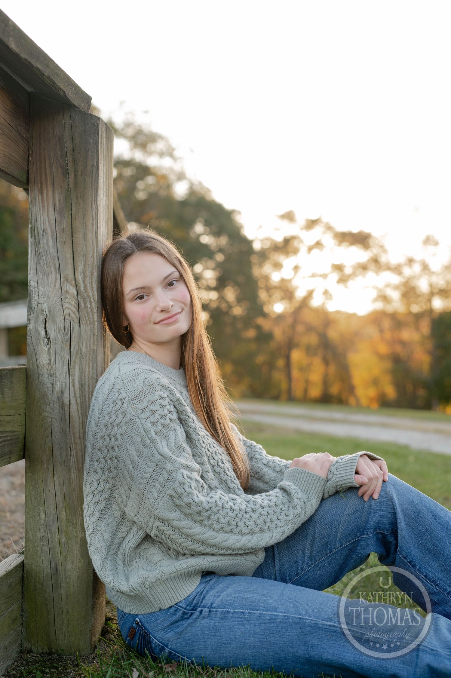 Someone in a cable knit sweater sits casually on wooden bleachers at sunset.