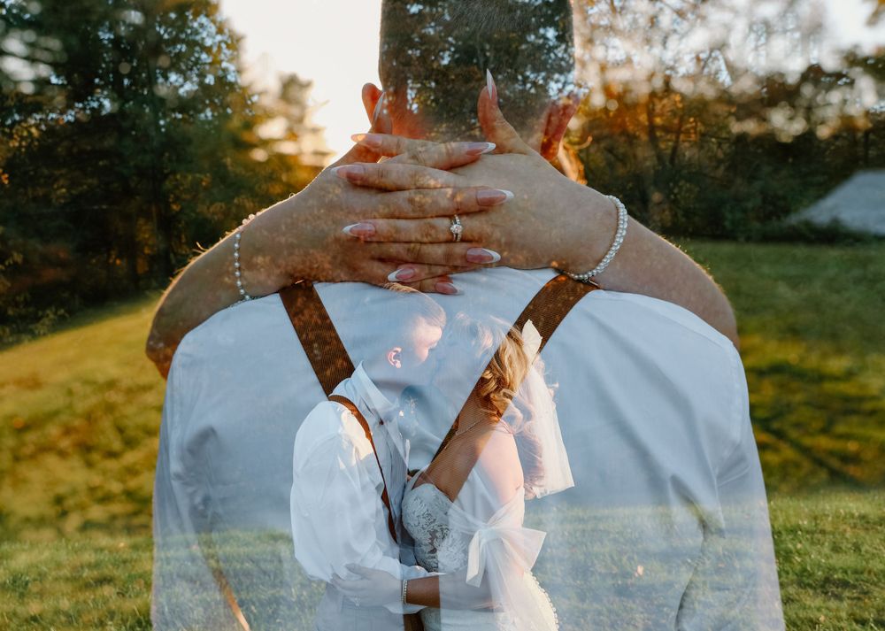 Hands clasped together against sunset light in romantic outdoor setting with suspenders visible.
