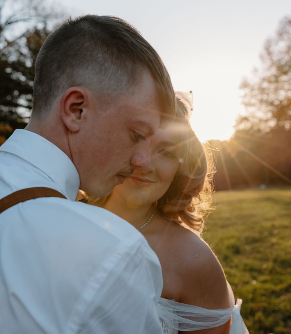 Golden hour portrait of couple embracing in backlit sunset glow.
