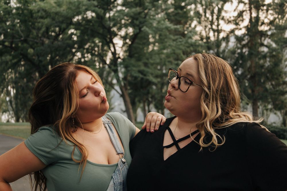 Two friends sharing a candid laughing moment during an outdoor photoshoot.