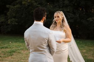 A wedding couple shares an intimate moment outdoors while dancing in their elegant white dress and grey suit.
