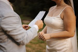 Several hands can be seen exchanging or passing papers during what appears to be a formal outdoor occasion.
