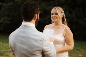 A couple dances together in an outdoor garden setting wearing elegant wedding attire.