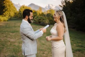 A couple exchanges vows during their outdoor mountain wedding ceremony at sunset in a meadow.