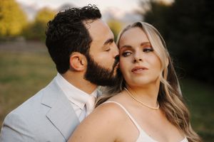 A couple shares romantic sunset kisses in a garden setting while wearing elegant wedding attire.