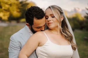 A romantic couple embraces in a golden-lit field during sunset, capturing an intimate moment together.
