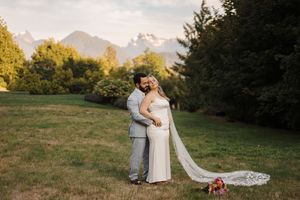 Wedding photo featuring mountain landscape with lush trees in background as couple shares intimate embrace at sunset.