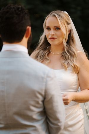 A close-up shot captures a bride in a white wedding dress with flowing veil against a dark background.