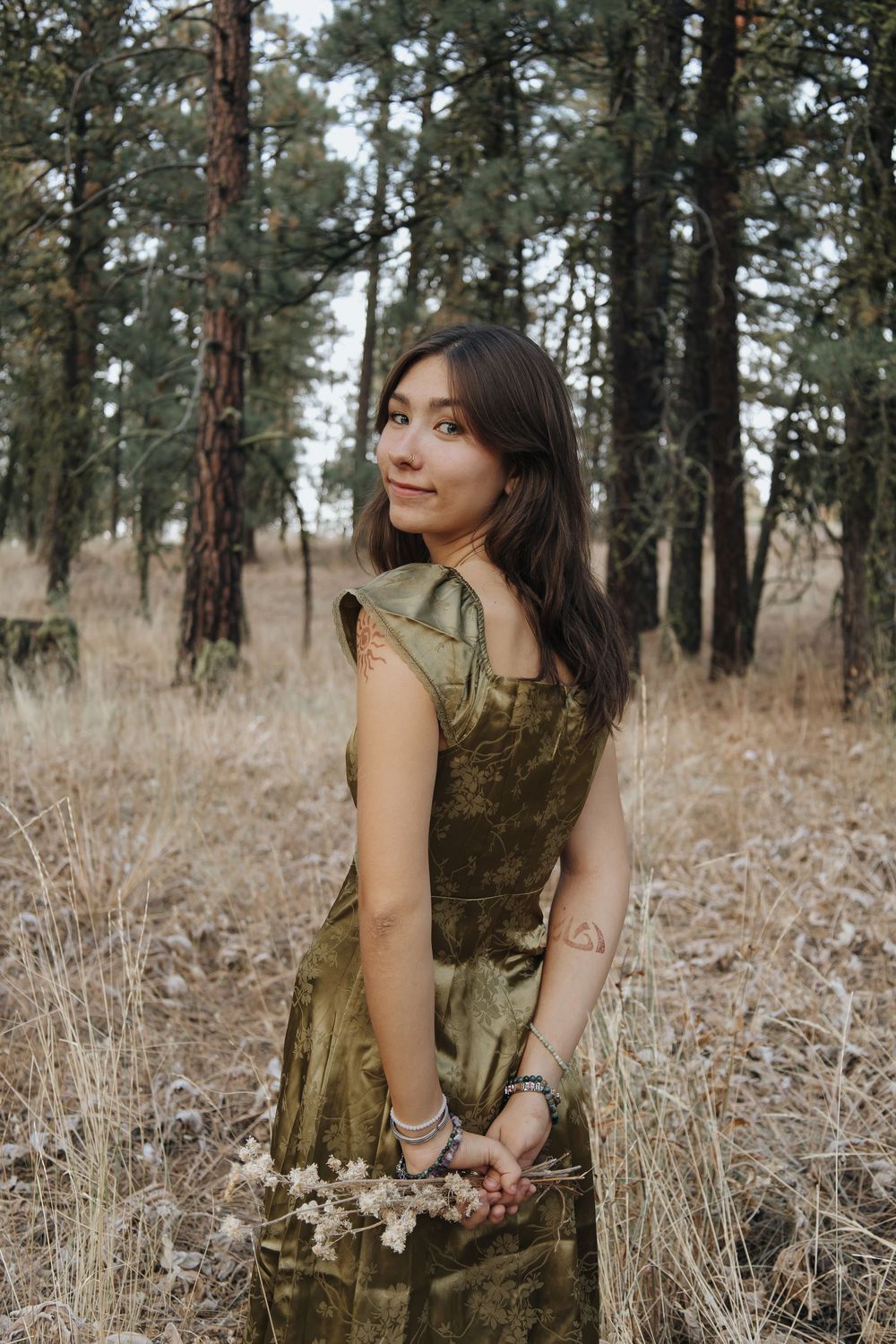 Autumn forest portrait in velvet dress among dried grass and pine trees.