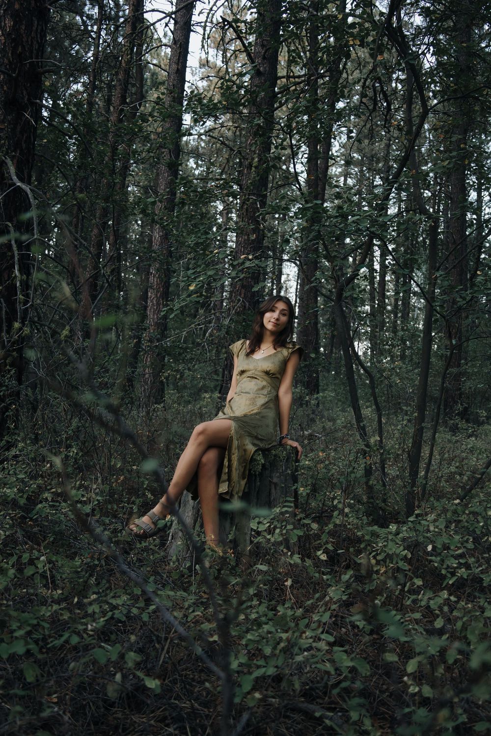 Artistic forest photoshoot sequence showing a person posing among dark trees and foliage.