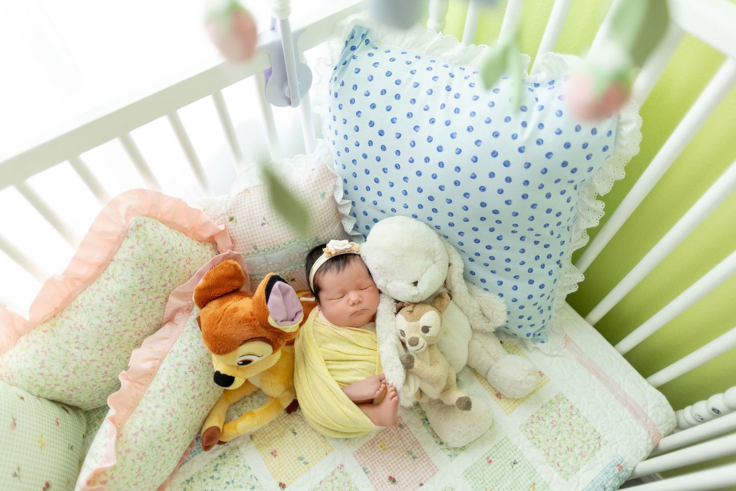 Pale mint and cream colored bedding and plush toys arranged in a cozy nursery setting.