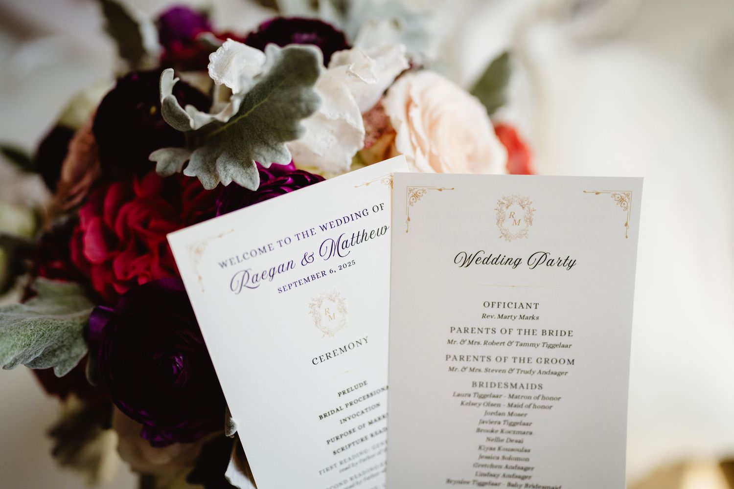 A collection of elegant white wedding invitation cards and stationery displayed with pink and burgundy flowers.
