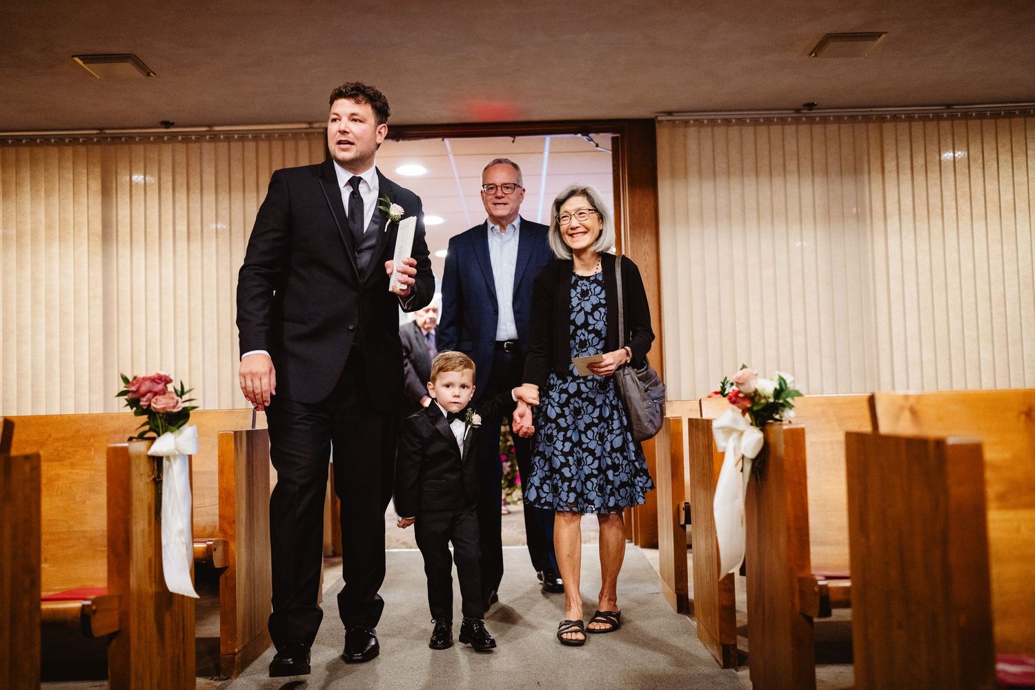 People enjoying a celebration in a banquet hall with wood paneled walls and pews.
