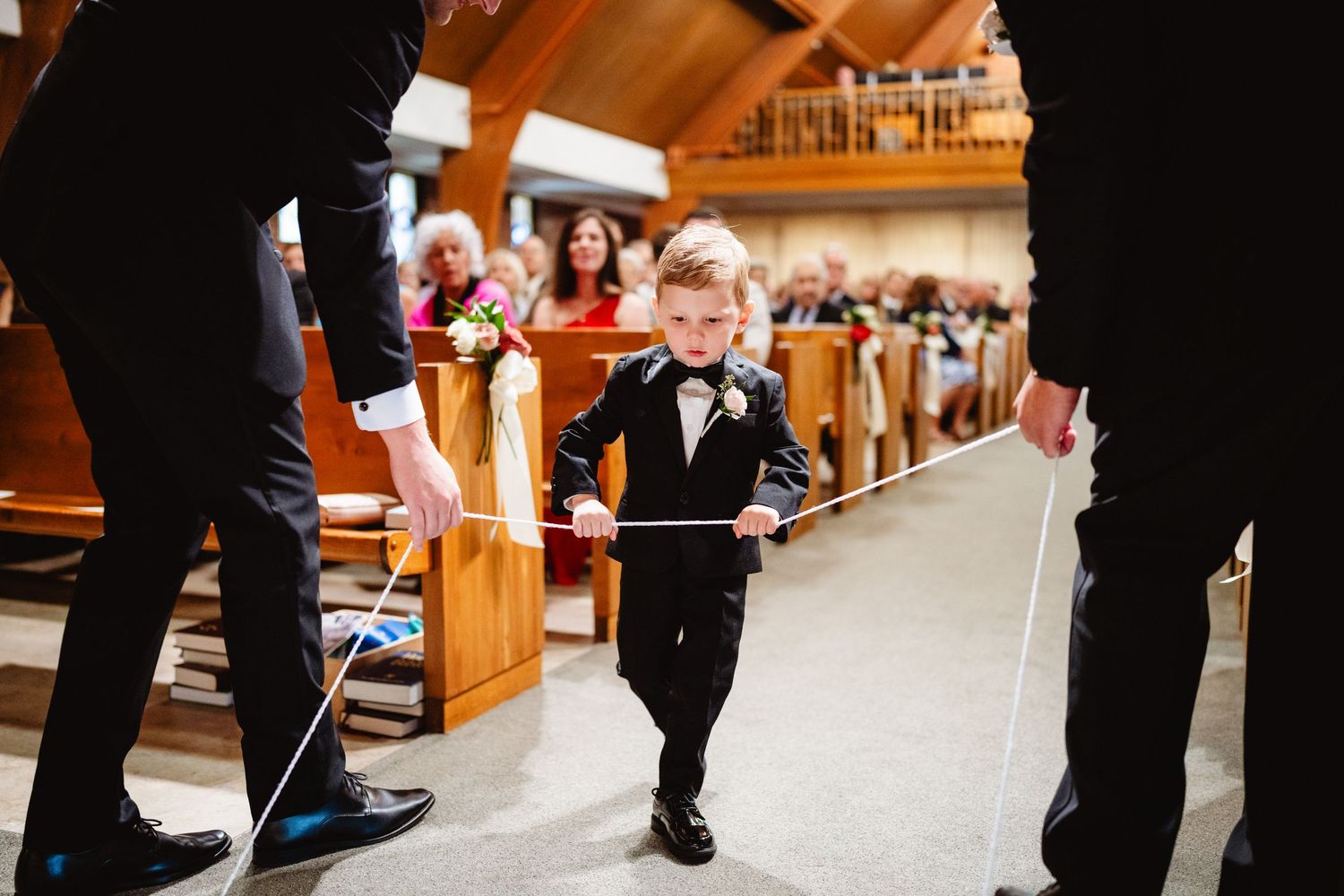 Church wedding ceremony as seen from the floor level showing guests' black dress shoes and formal attire.