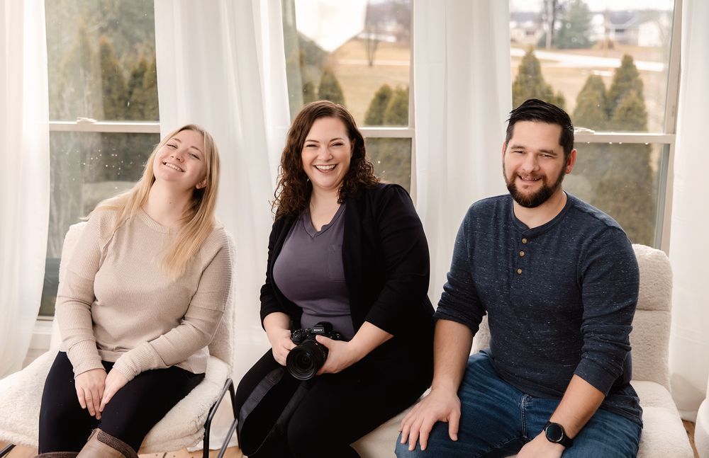 Group relaxes together on white porch during casual outdoor photo session.