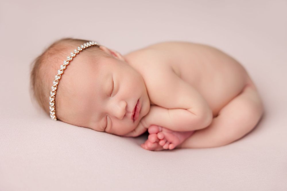 Artistic series of newborn baby photos showing peaceful sleeping poses against a soft pink backdrop.