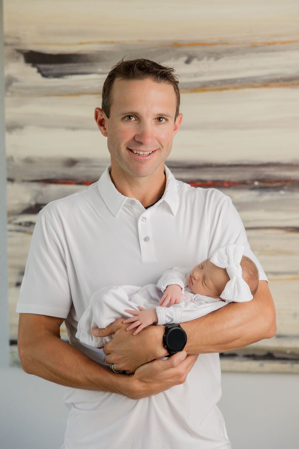 A person in a white polo shirt holds a sleeping newborn baby in 4 similar poses against a light backdrop.