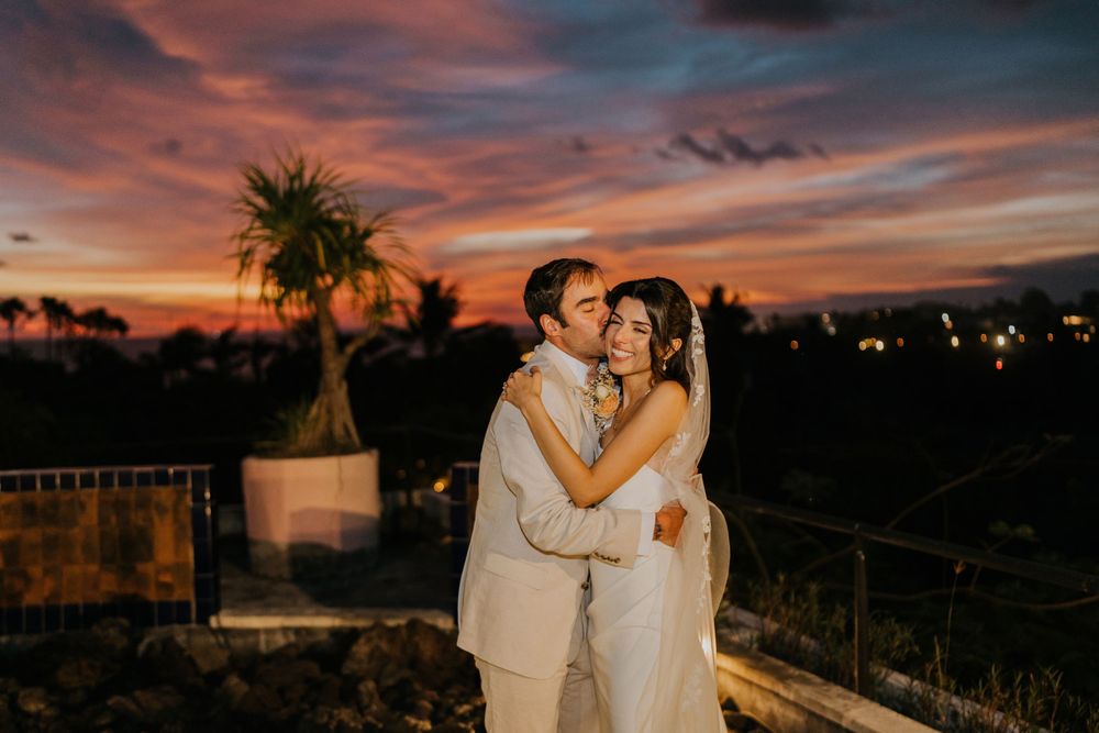 Romantic sunset ceremony with palm trees silhouetted against colorful evening sky.