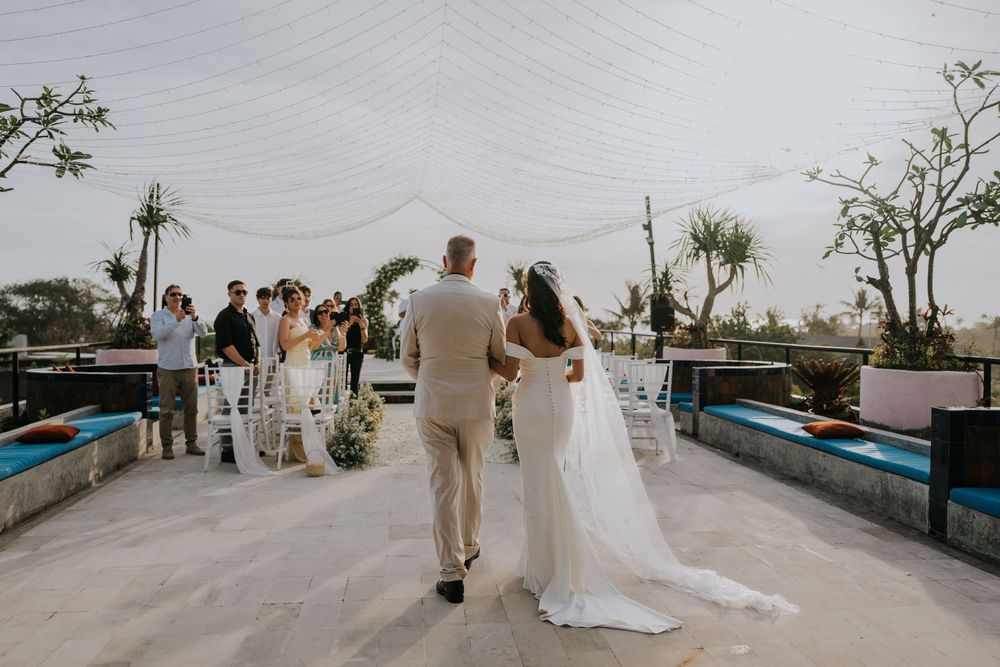 Wedding ceremony setup with ocean view and palm trees in background.