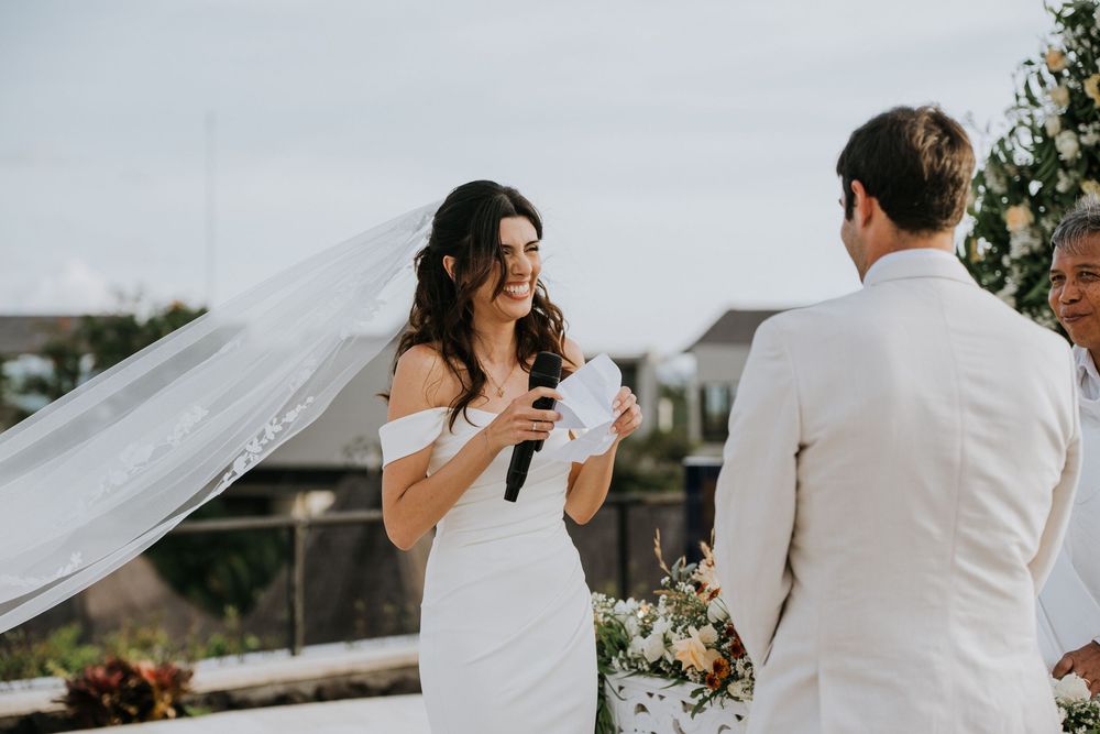 Wedding celebration on oceanfront terrace with flowing veil in breeze.