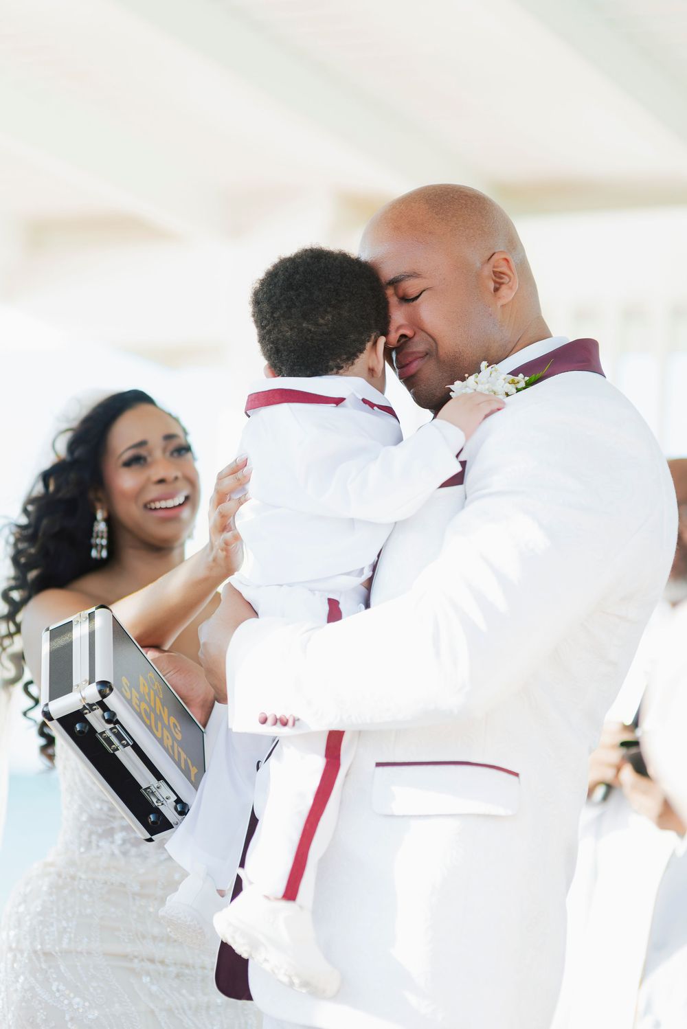 A joyful wedding moment captured as a couple embraces while celebrating with their child during the ceremony.