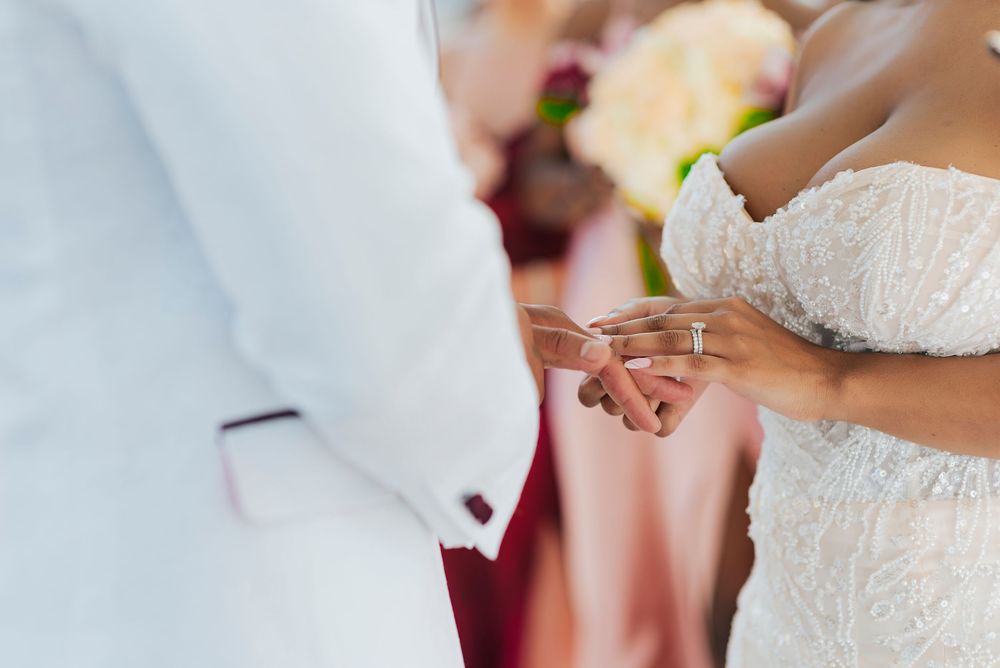 Close-up details of a white lace wedding dress and bridal accessories on a sunny day.