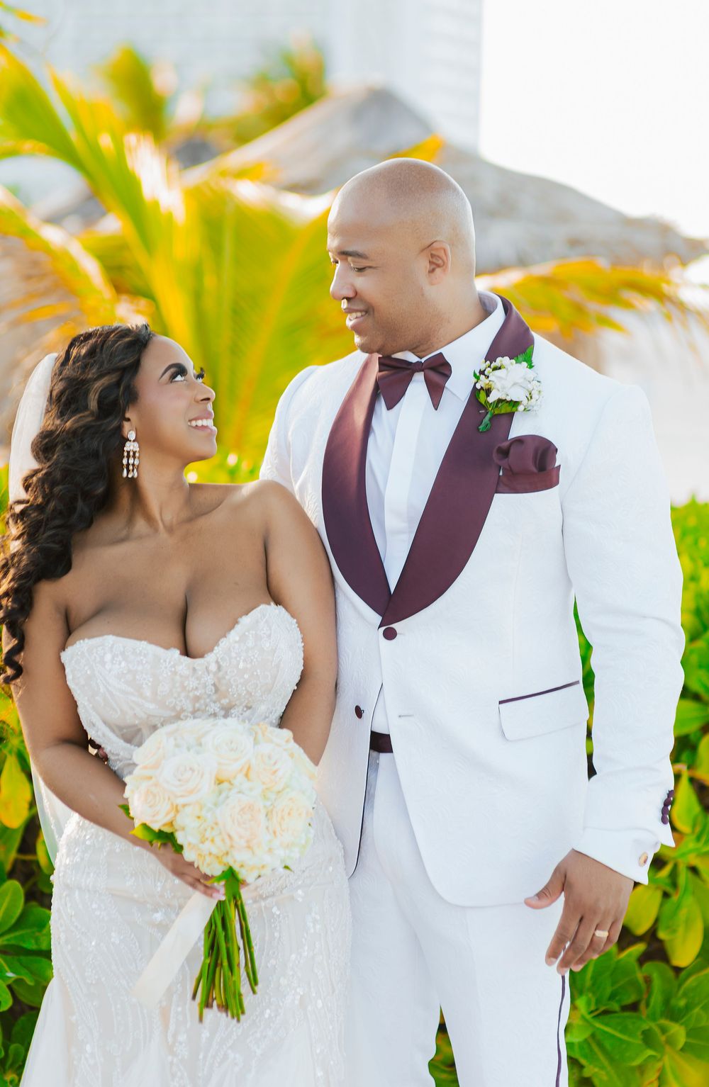 A romantic wedding photo series showing a couple in white and burgundy attire posing against tropical palm trees.