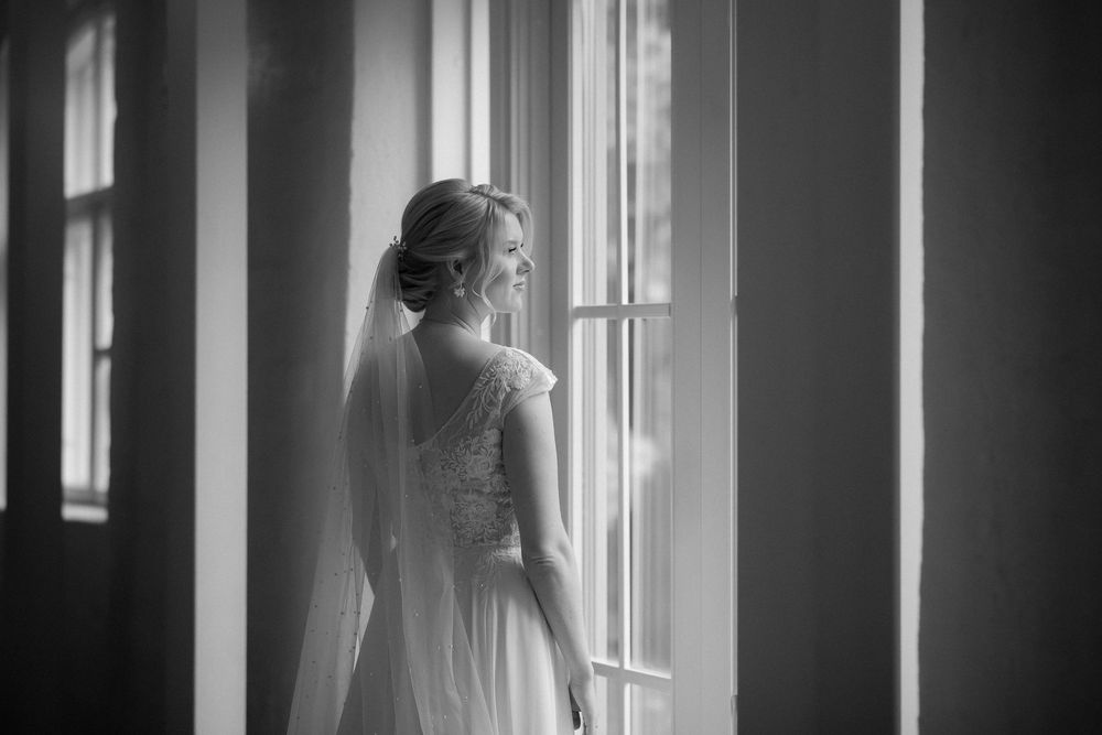 Multiple artistic black and white shots capture light and shadow on someone wearing a bridal gown near a window.