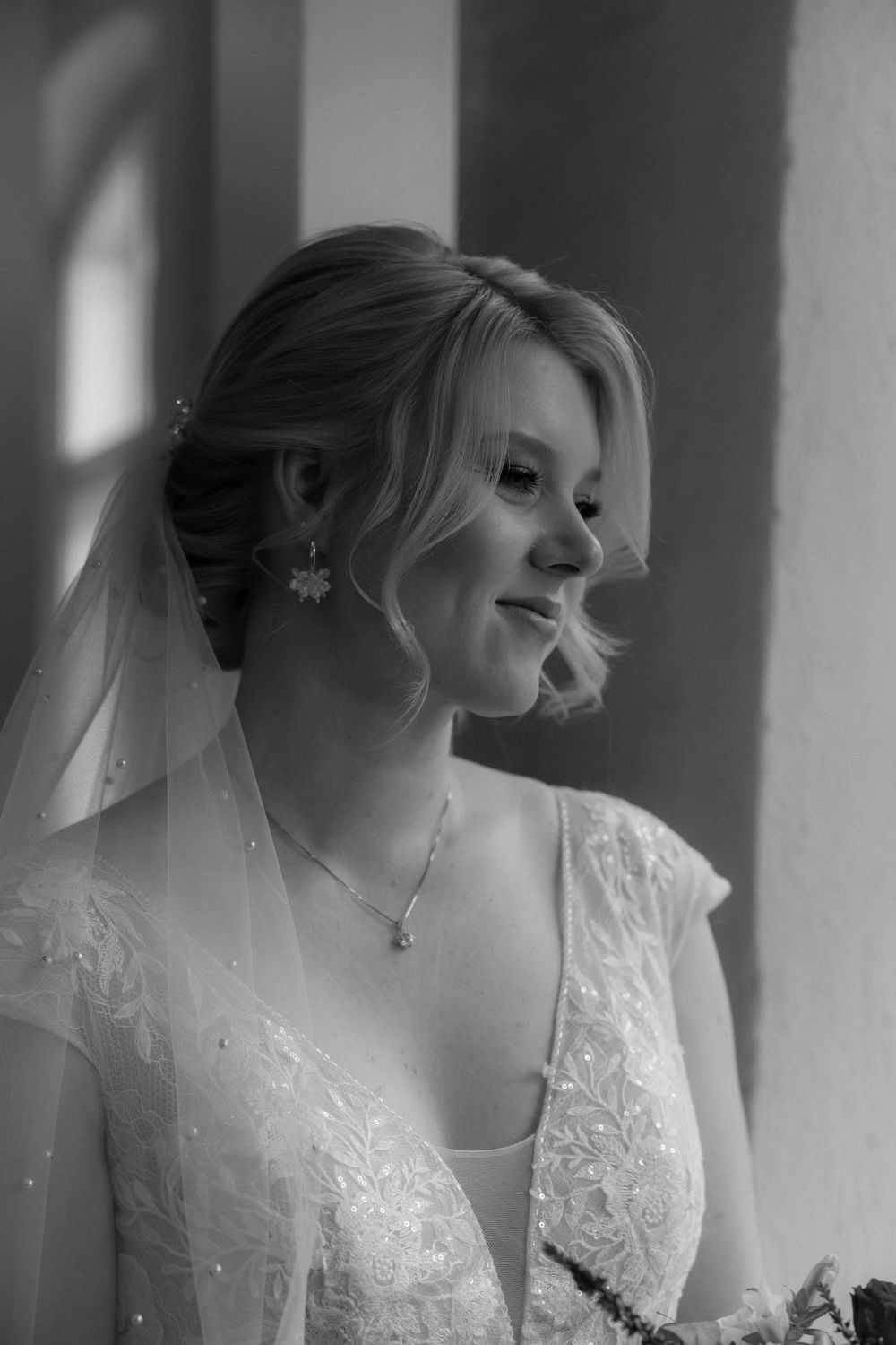 A sequence of black and white portraits showing someone in a delicate lace wedding dress gazing by a window.