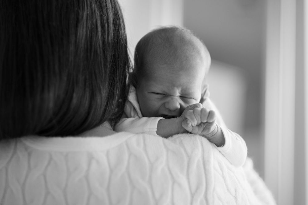 A series of black and white intimate family moments showing close interactions between figures in a home setting.