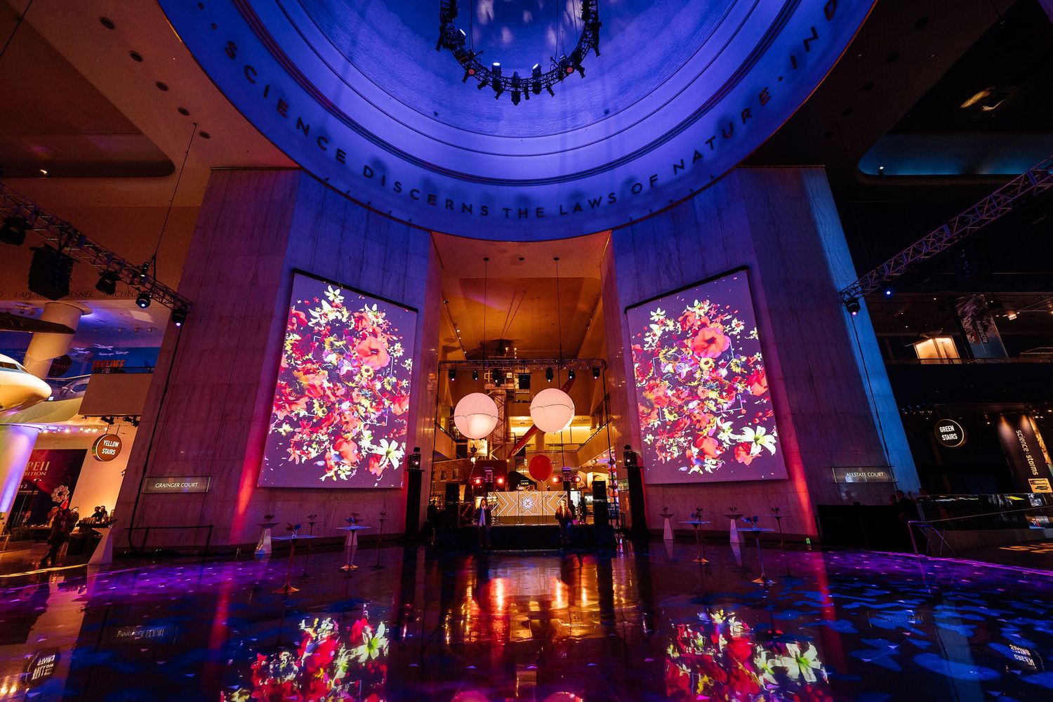 Luxurious event space with illuminated pink floral displays and dramatic lighting creating reflections on the floor.