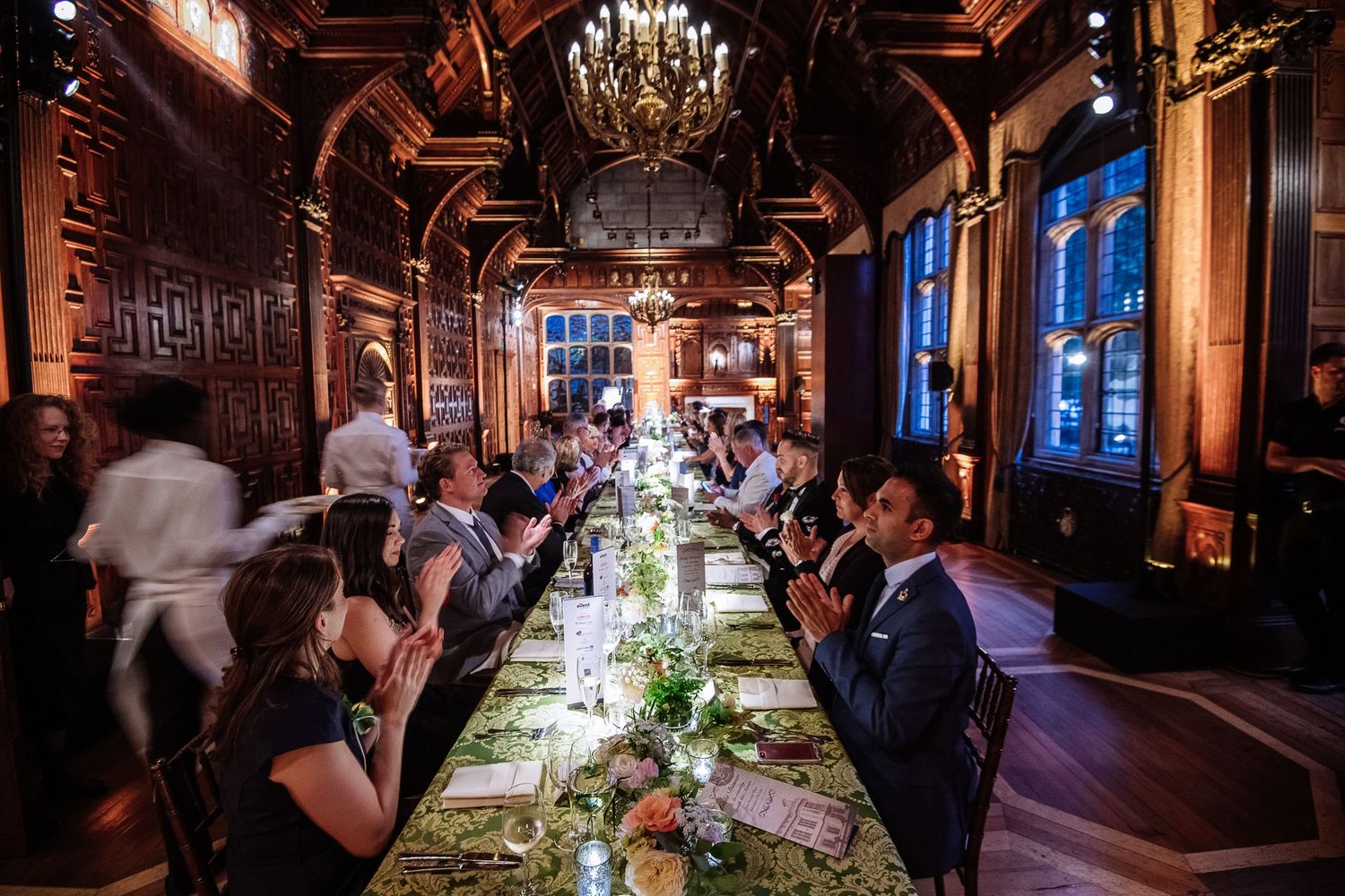 Elegant wood-paneled dining room with chandelier and long table set for formal dinner service.