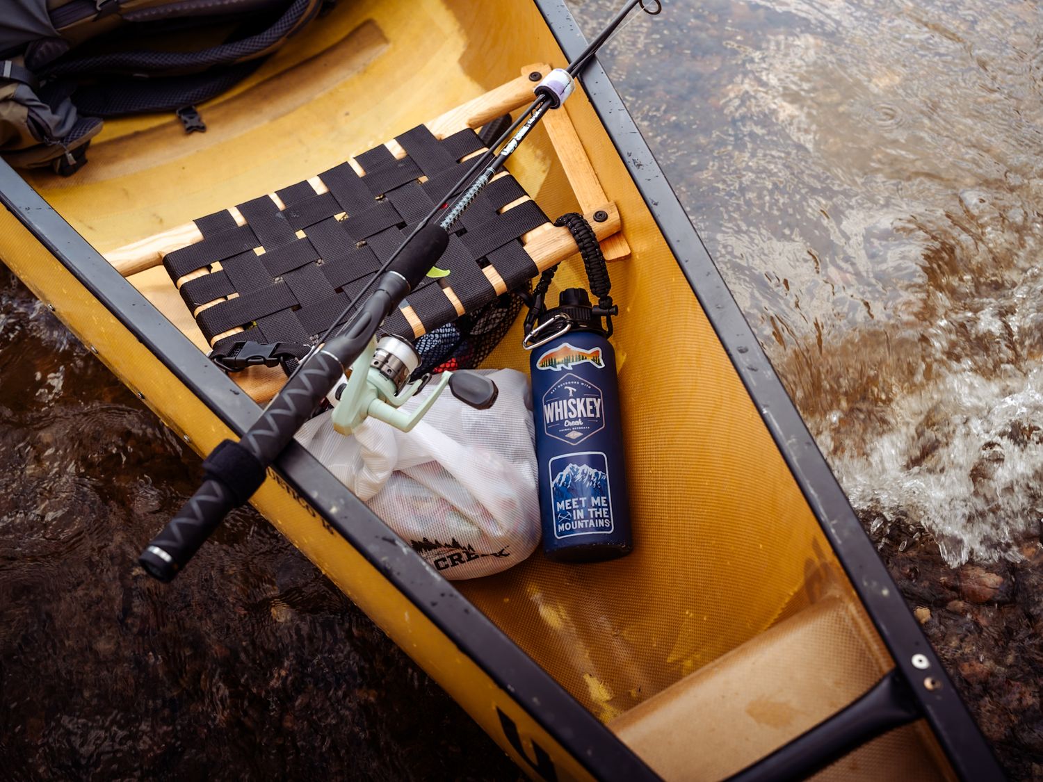 Jack Daniels whiskey bottle and glasses in rustic setting against wooden surface with warm lighting.
