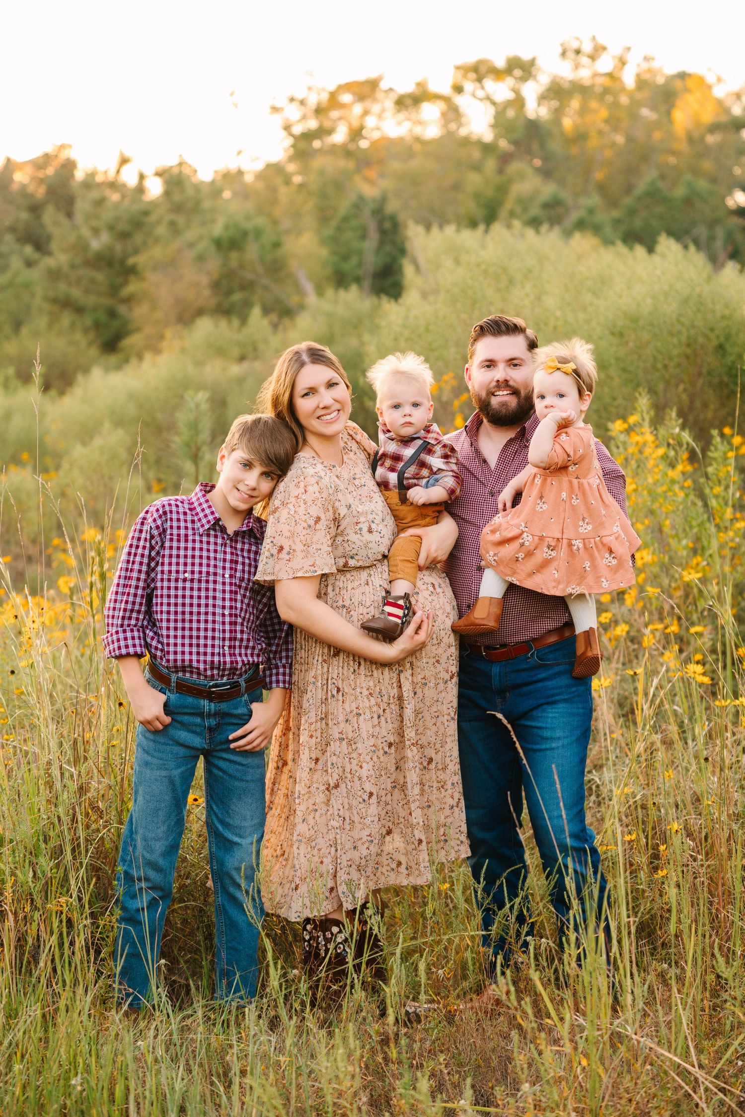 Group portrait in a golden field with tall wildflowers during sunset.