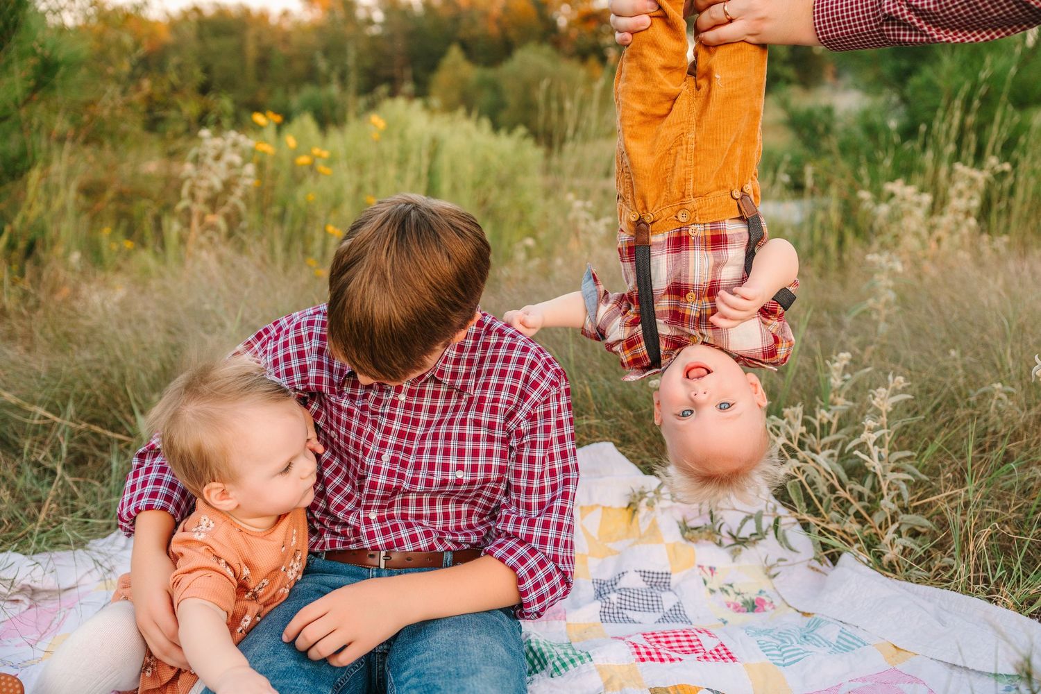 A family enjoys quality time together during a cozy autumn picnic outdoors on a patterned blanket.