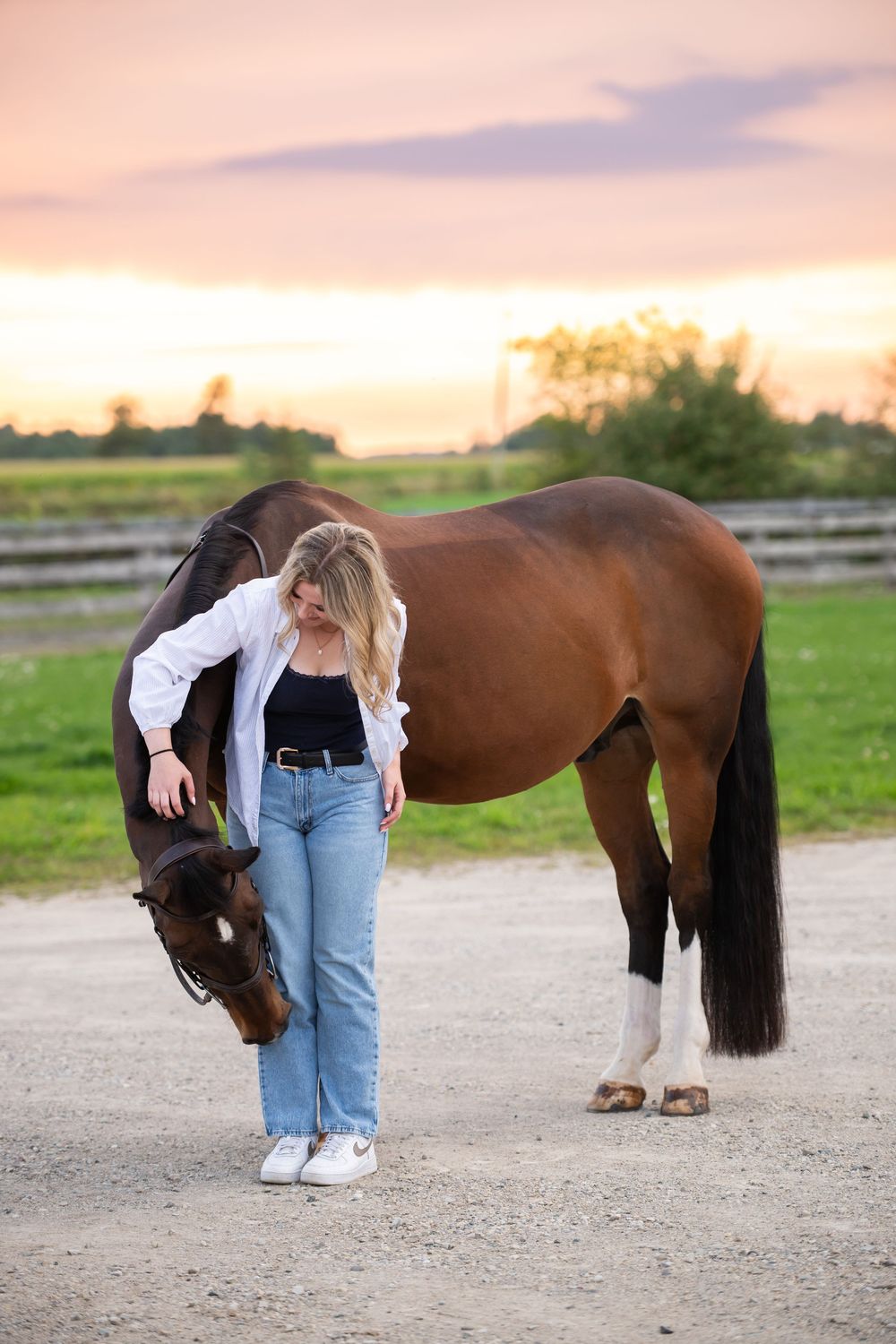 Horse and woman share a quiet bonding moment at sunset in an outdoor paddock.