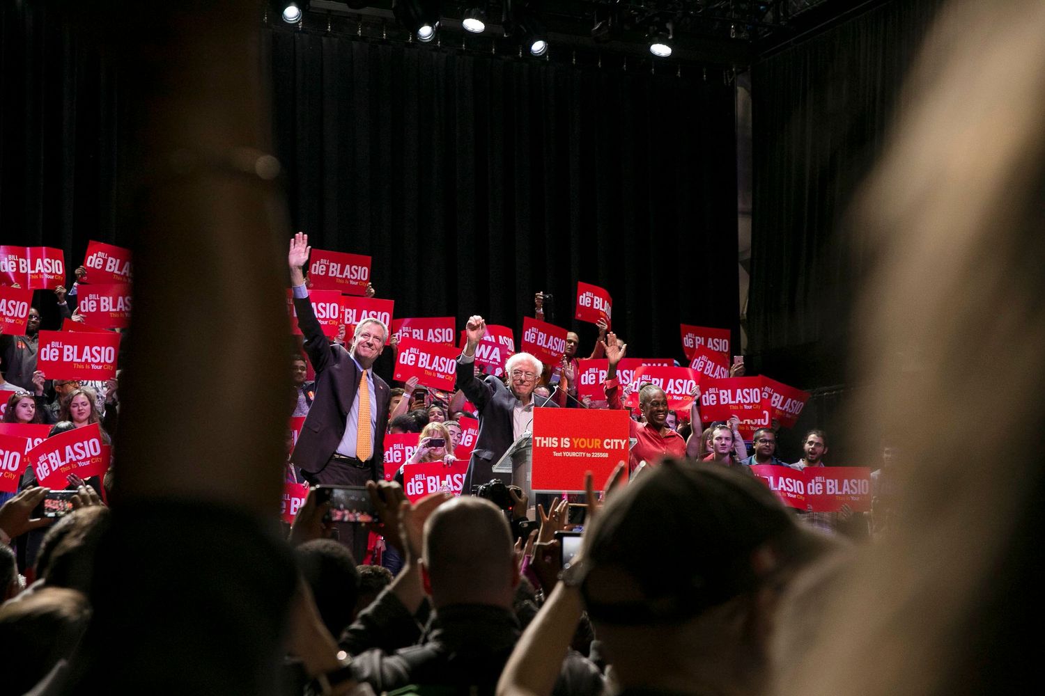 Large audience facing red illuminated stage during an indoor performance event.
