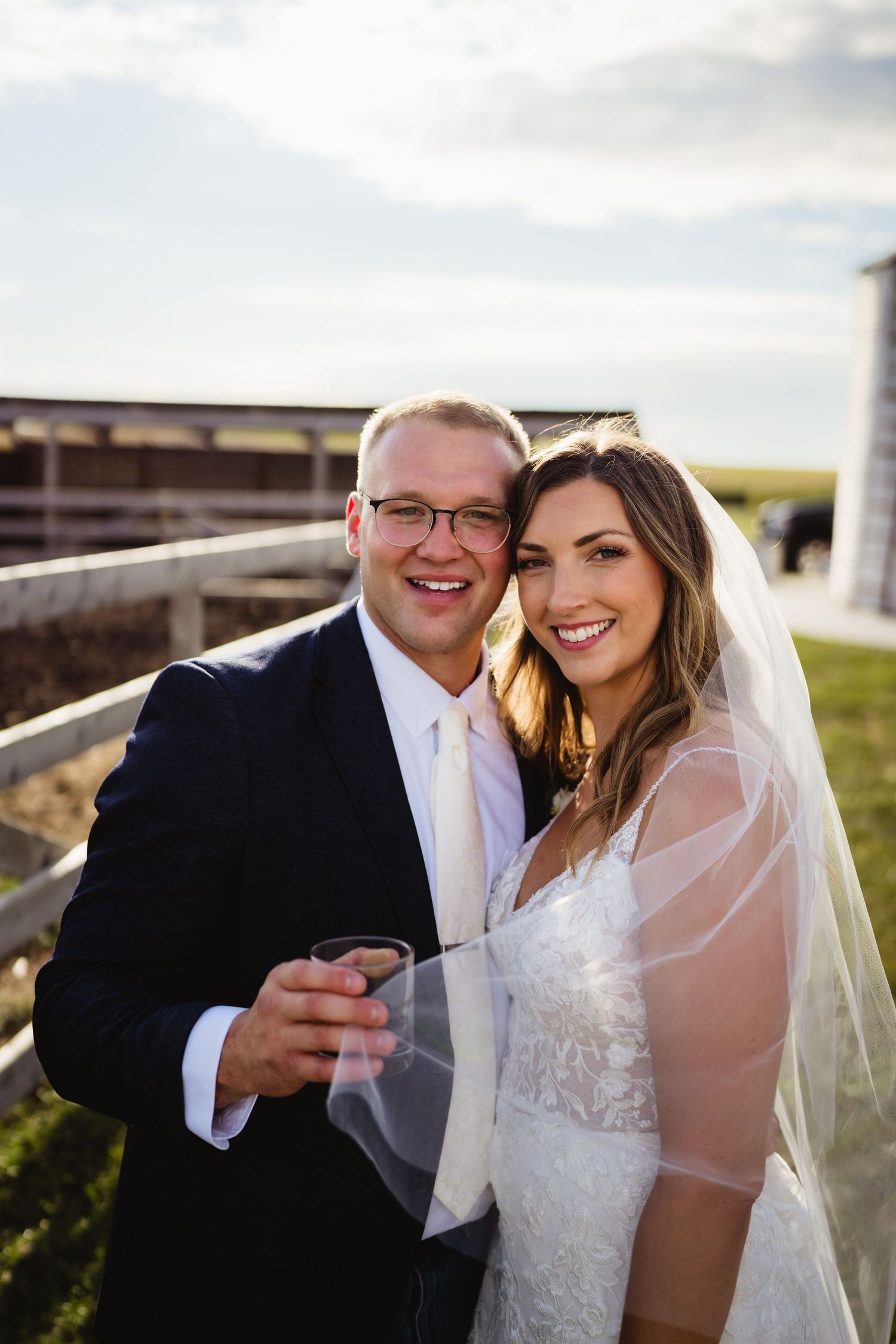 A newlywed couple shares intimate moments together on their wedding day in a countryside setting at sunset.