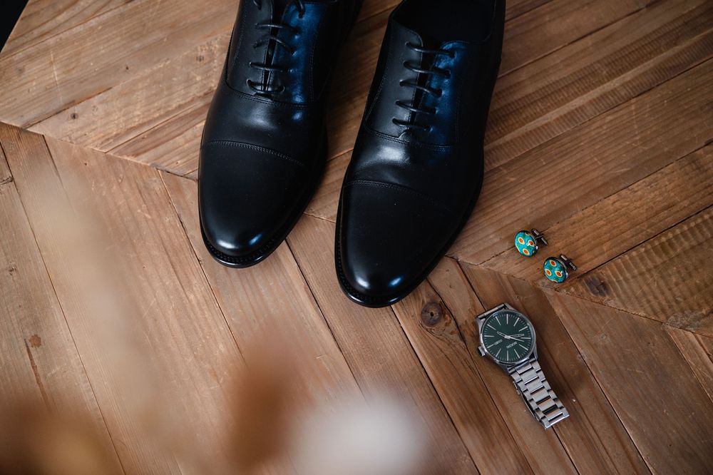 Close-up view of black leather dress shoes on wooden parquet flooring.