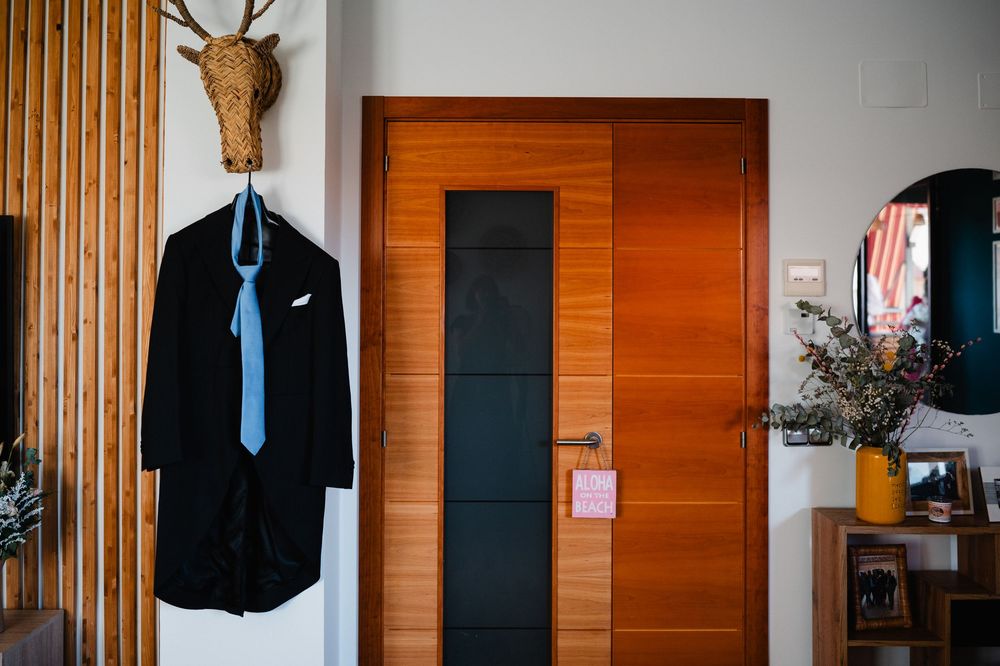 Modern wooden wall panels with black suit jackets hanging on display in interior space.