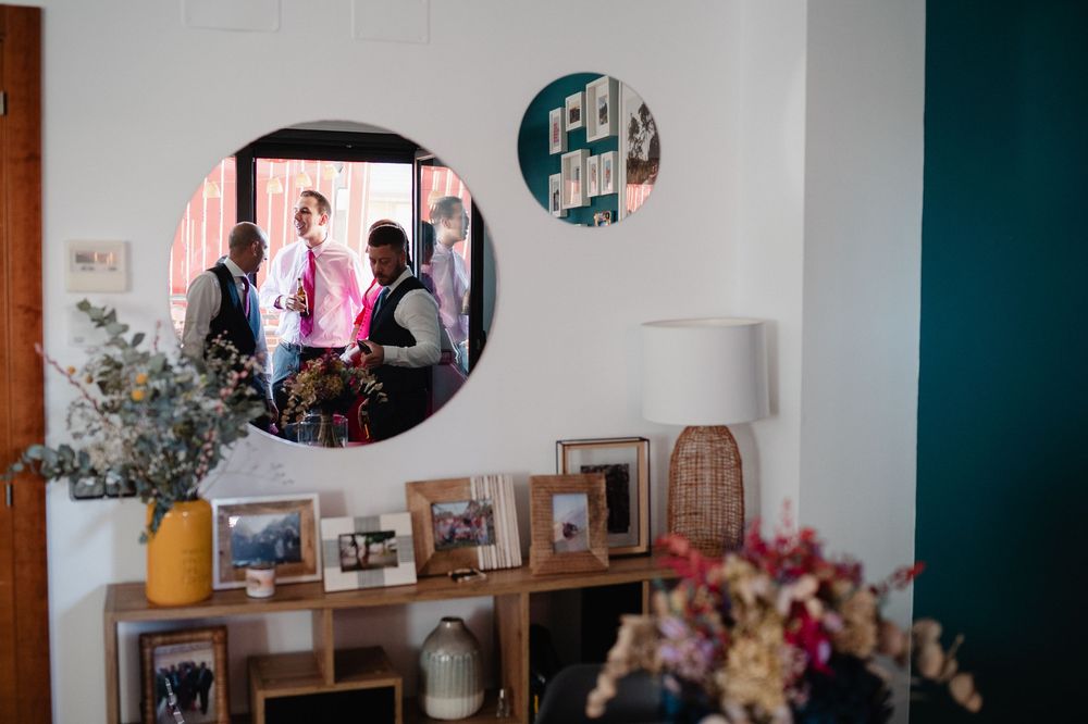 An eclectic corner of a room decorated with vintage pieces, plants, and photographs on white walls.
