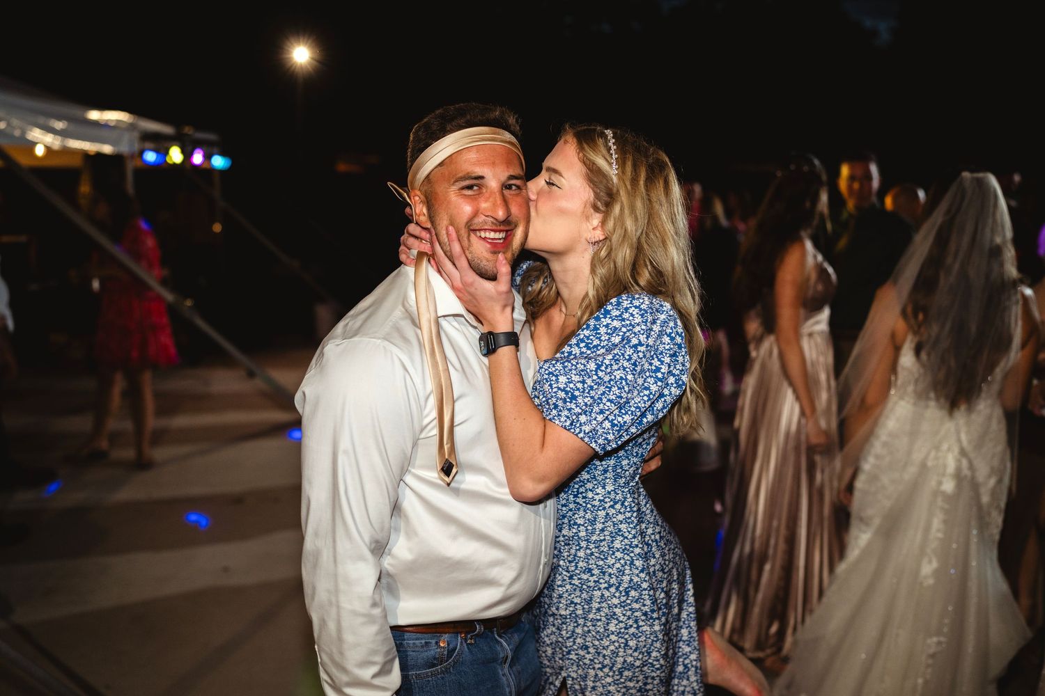 A couple dances together at night during an outdoor event.