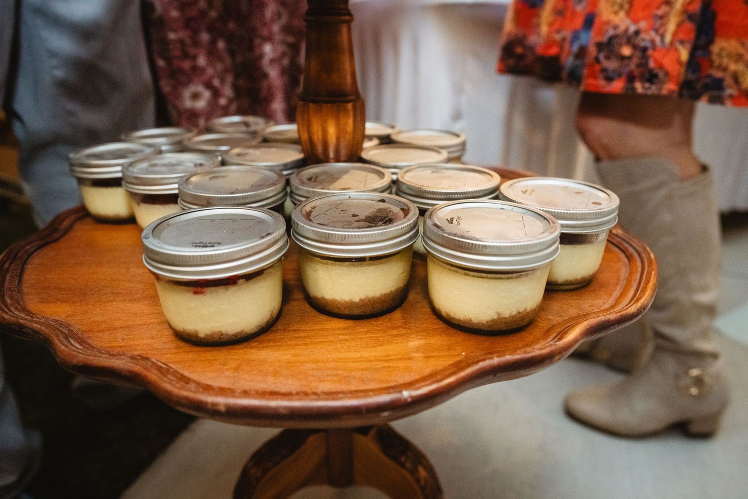 Glass jars of homemade cheesecakes arranged on a rustic wooden serving board.