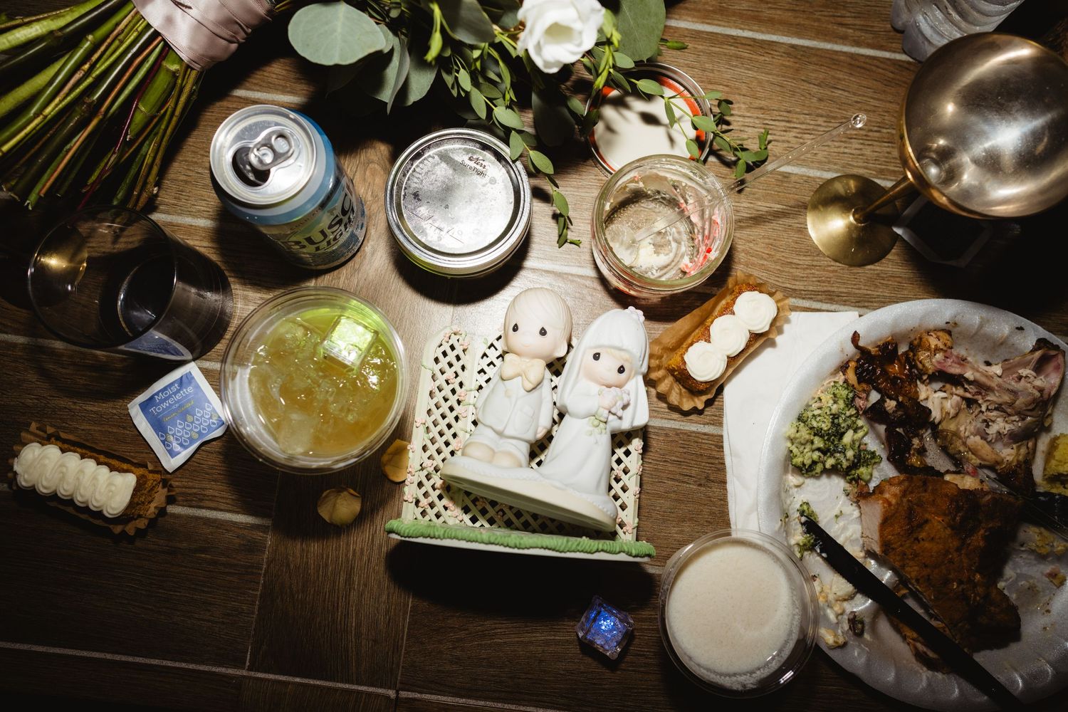 Overhead view of beer bottles and snacks on a rustic wooden table at night.