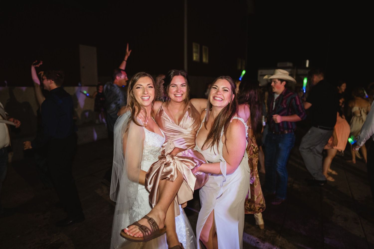 People dancing and celebrating at a lively nighttime party or event with colorful lighting.