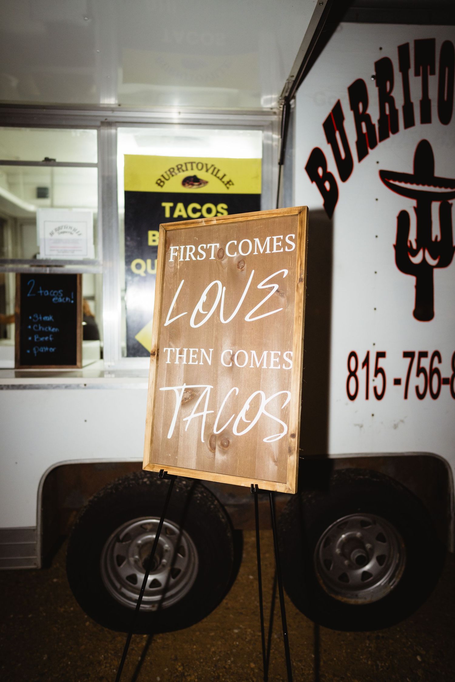 A series of lighted signs on a food truck showing progressive text that reads 'First comes love, then comes tacos'.