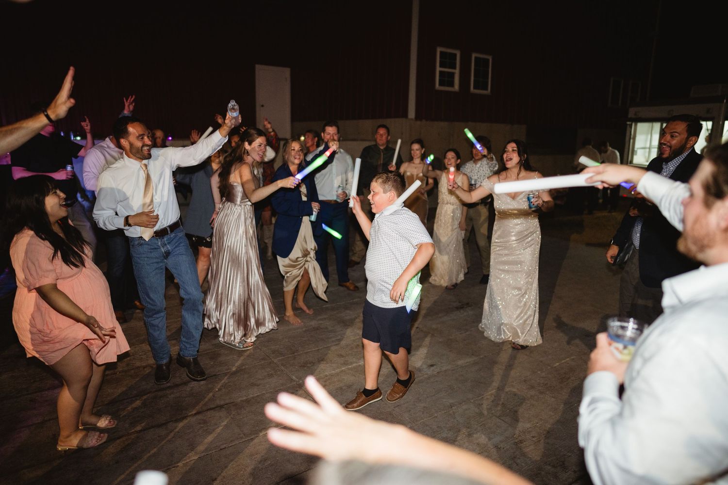 A group of people dancing together during a lively celebration on a dark dance floor.