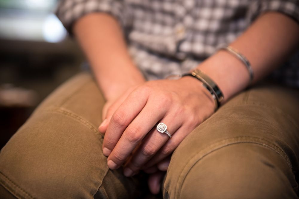 Close-up view of hands with wedding ring resting on khaki pants.